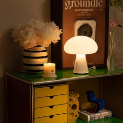 Modern white mushroom table lamp with three-color light on a green shelf, styled with a vase of flowers and candle, from YH Lamps.