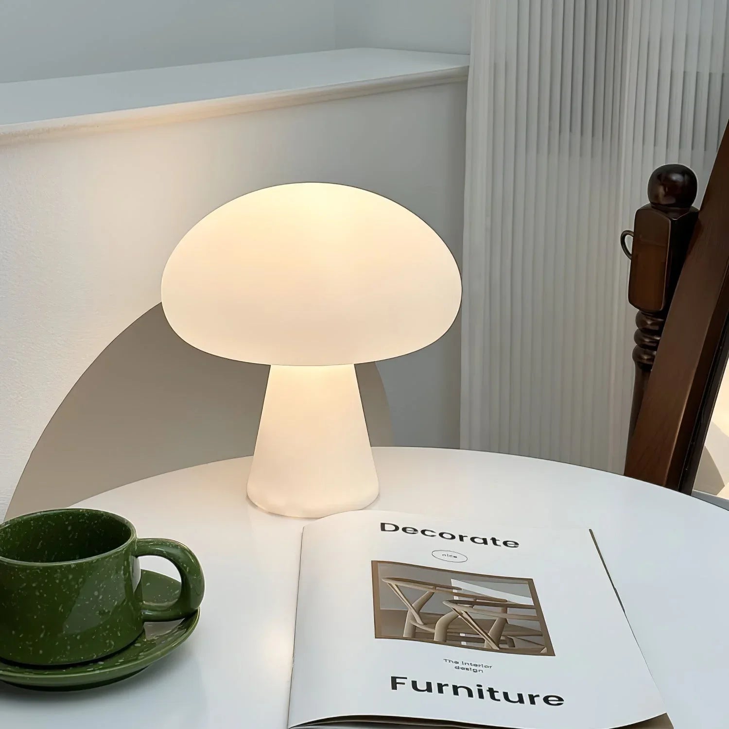 Modern white mushroom table lamp with three-color light on a round table beside decor magazine