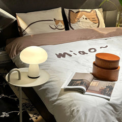 Modern white mushroom table lamp on bedside table in cozy bedroom with cat-themed bedding