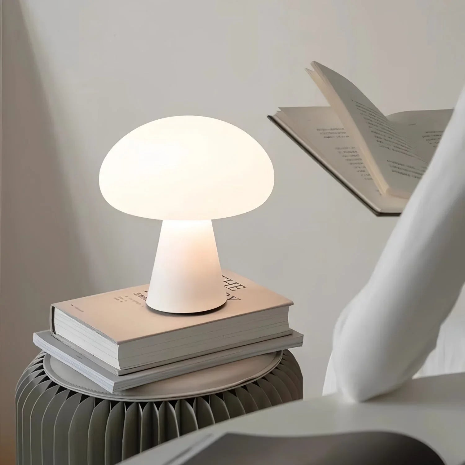 Modern white mushroom table lamp from YH Lamps on books beside a person reading