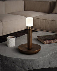Modern wood and brass table lamp with frosted glass shade on stone coffee table in cozy living room