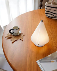 Modern white cone-shaped table lamp on wooden table with coffee cup and magazine, YH Lamps