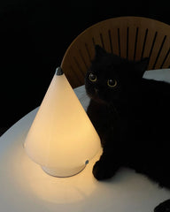 Modern white cone table lamp with touch switch on a white table beside a black cat, YH Lamps