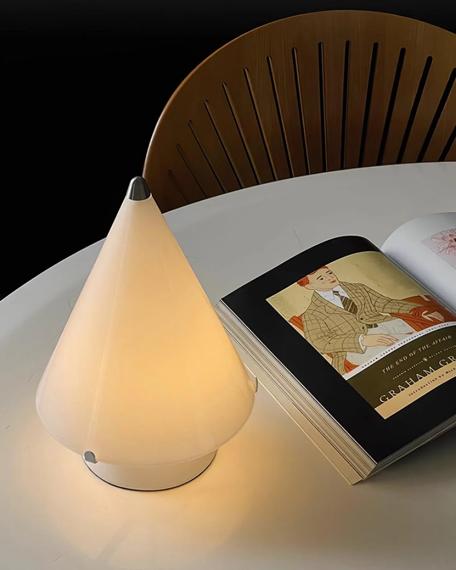 Modern white conical table lamp with touch switch on round table beside open book and chair