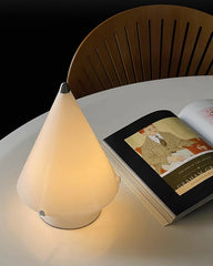 Modern white conical table lamp with touch switch on round table beside open book and chair