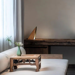 Modern triangular wooden table lamp with warm light on rustic desk in minimalist living room