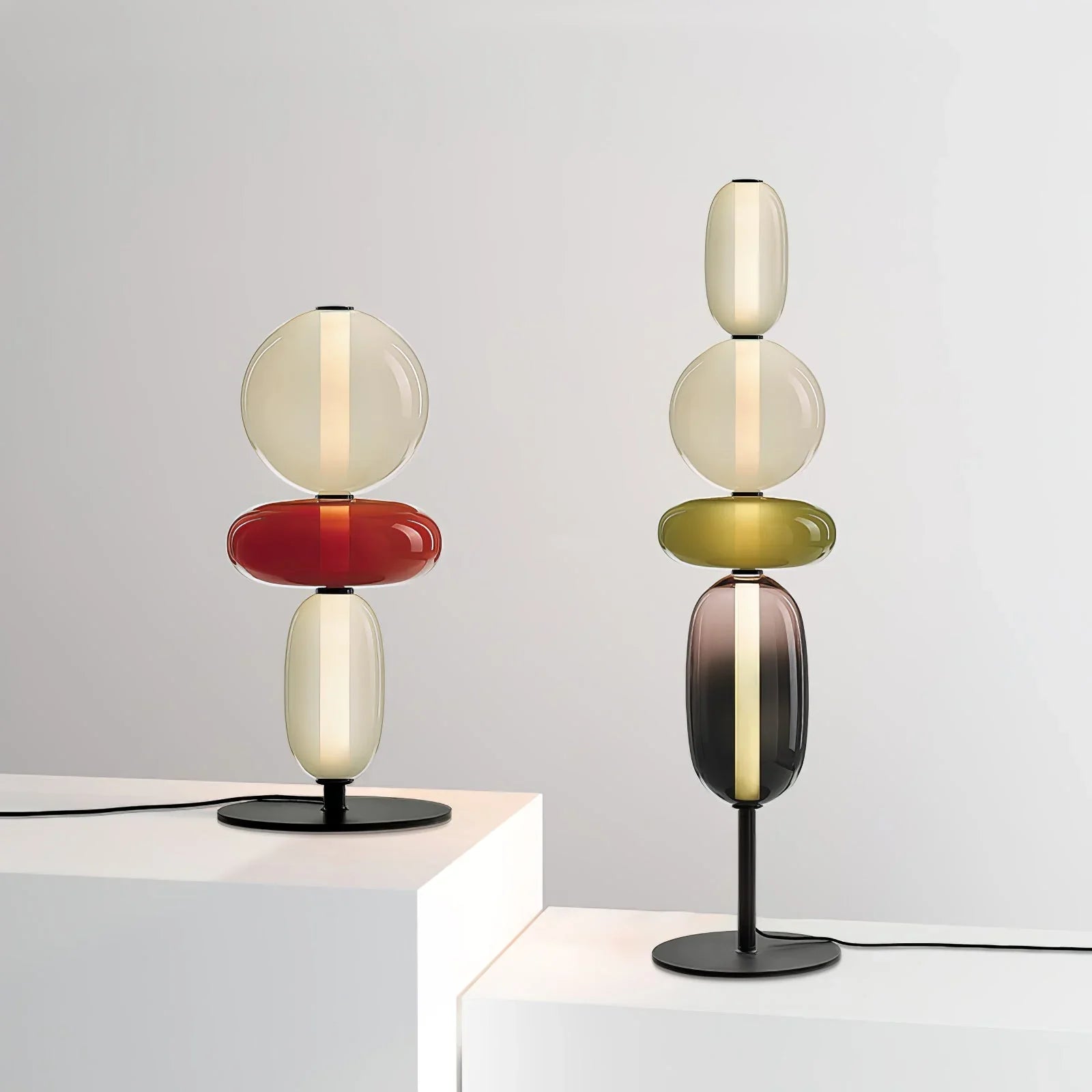Modern table lamps with stacked oval and round candied glass shades in warm light on black metal bases
