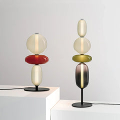 Modern table lamps with stacked oval and round candied glass shades in warm light on black metal bases