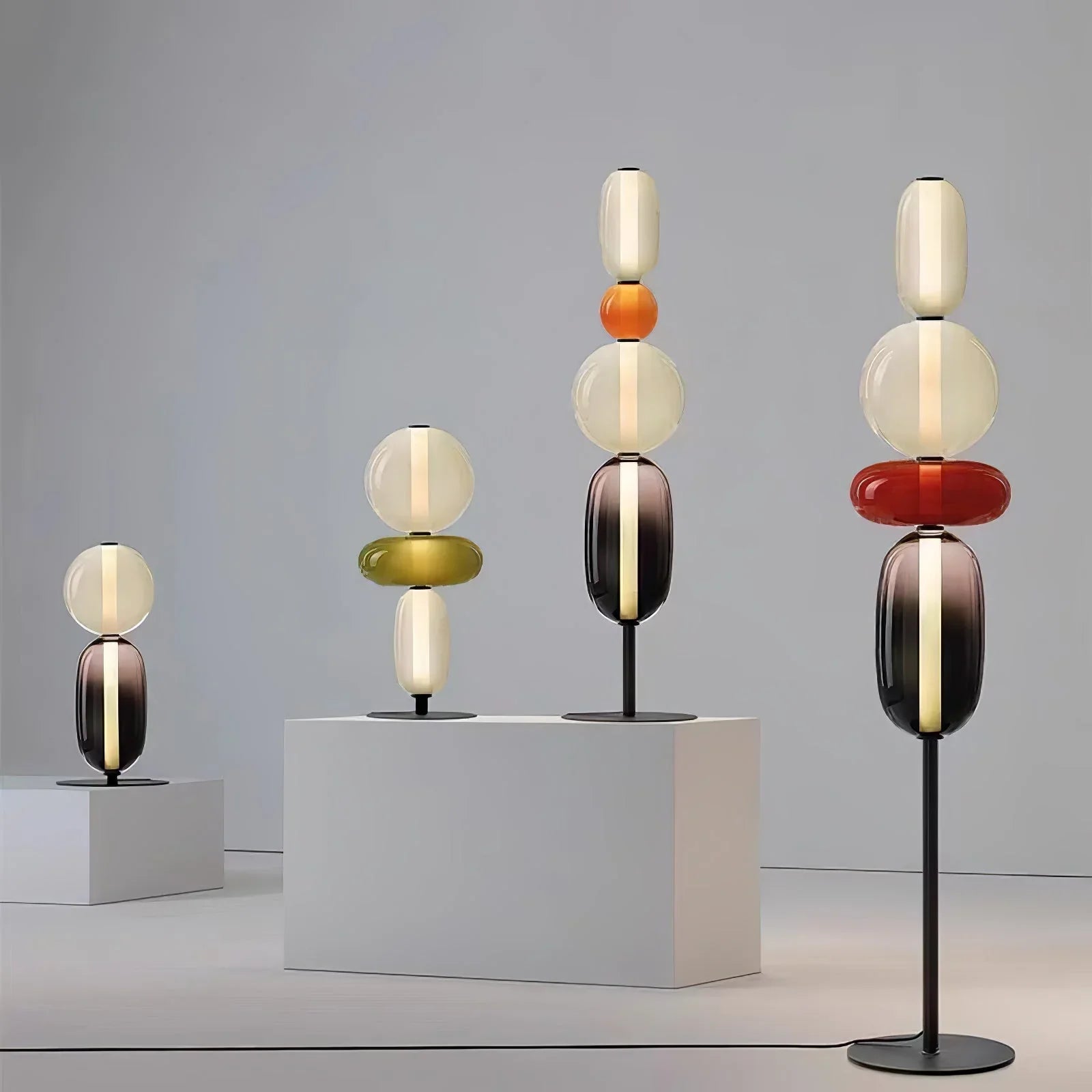 Set of modern colorful glass table and floor lamps with vertical LED lights on white pedestals
