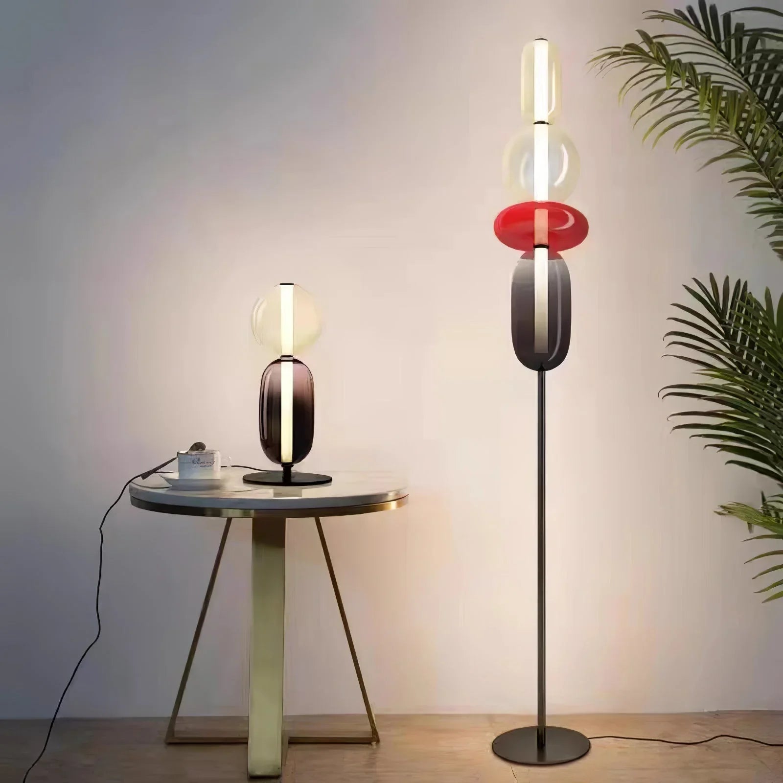 Modern table lamp on round side table and matching floor lamp with colored glass elements in minimalist room
