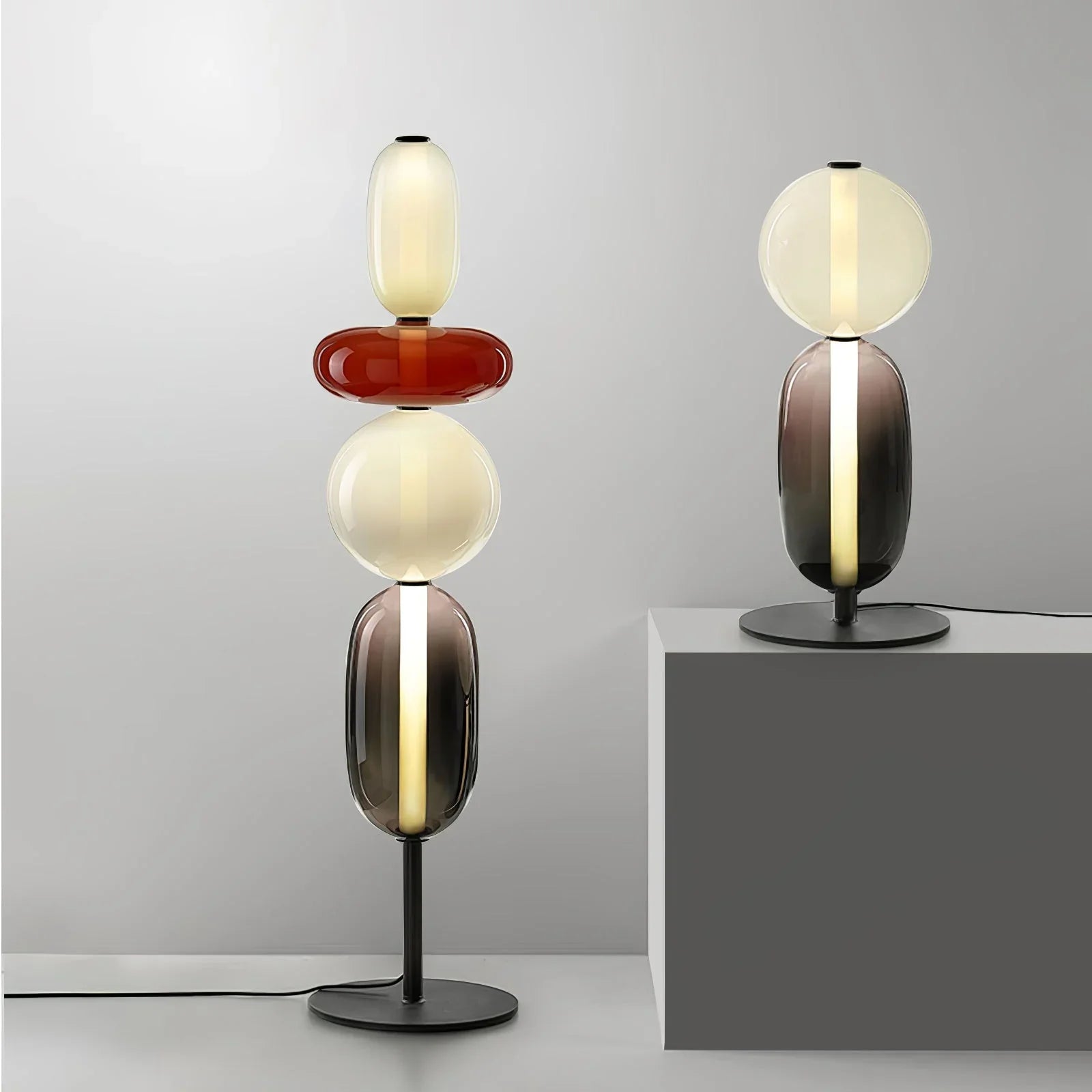 Modern artistic table lamps with stacked colored glass shapes and warm light on black metal bases