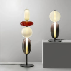 Modern artistic table lamps with stacked colored glass shapes and warm light on black metal bases