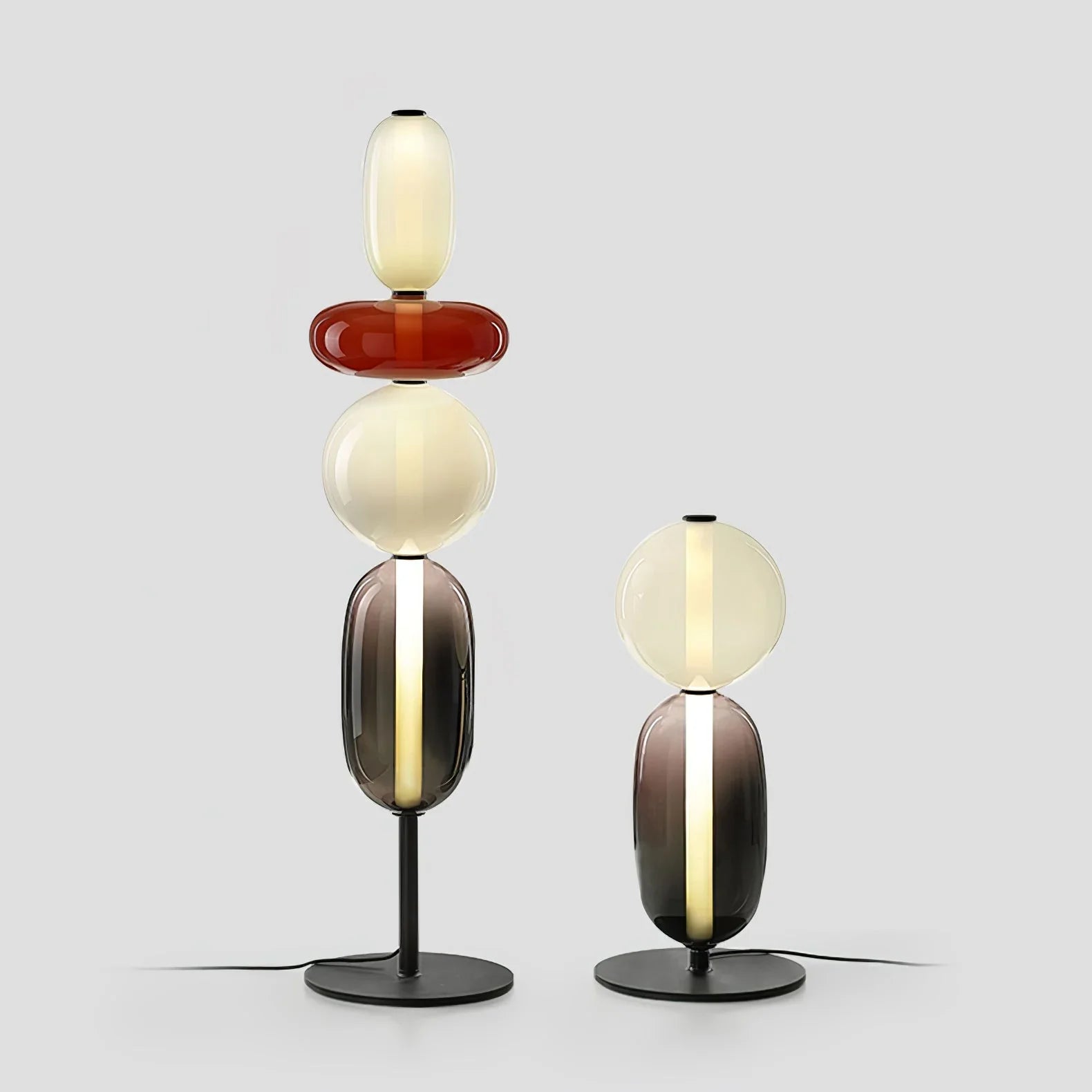 Modern table lamps with stacked oval candied glass shades in warm light on black metal bases