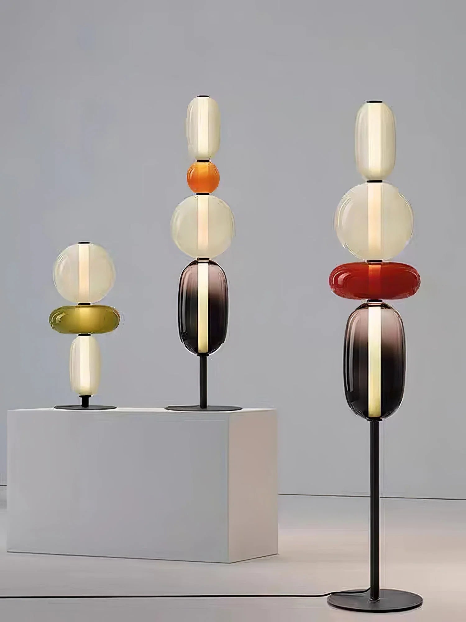 Modern artistic table lamps with stacked oval glass shades in warm colors on black metal stands