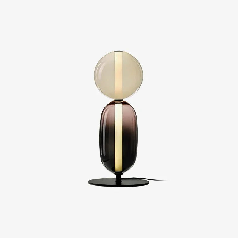 Modern table lamp with warm light, featuring two stacked candied glass forms in amber and dark hues on a black base