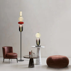 Modern living room with YH Lamps floor lamp and table lamp featuring colorful glass shades, leather chair, marble tables, and round pouf