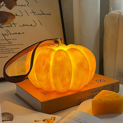 Yellow pumpkin-shaped portable table lamp with leather strap, USB, on books by YH Lamps