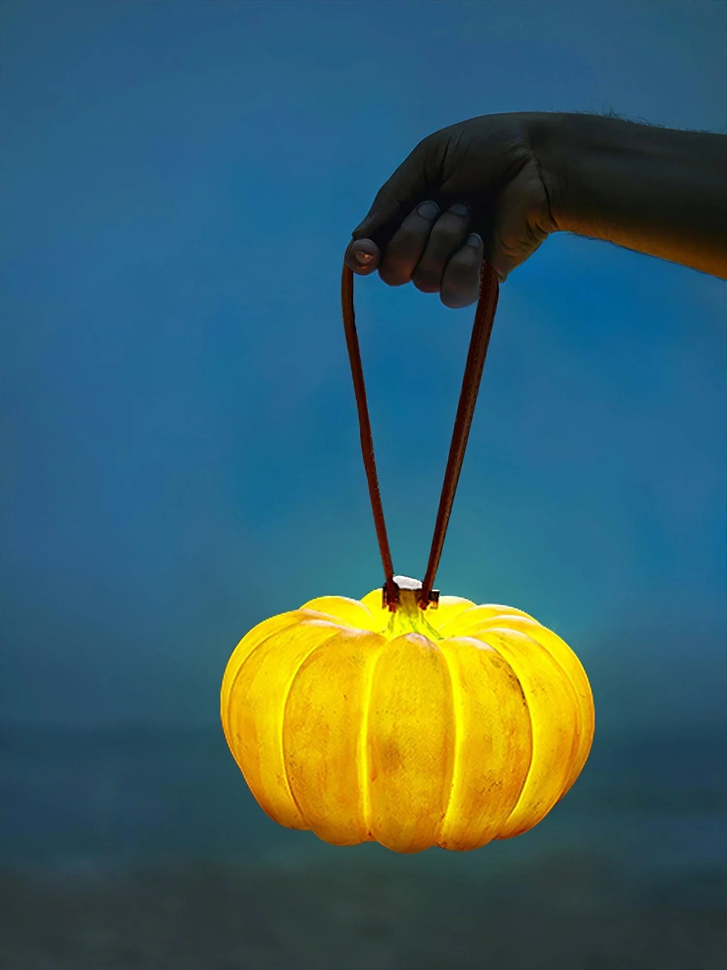 Hand holding yellow pumpkin-shaped portable table lamp with leather handle, YH Lamps