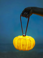 Hand holding yellow pumpkin-shaped portable table lamp with leather handle, YH Lamps