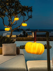 Modern yellow pumpkin-shaped portable table lamp with USB, glowing outdoors on a patio at dusk, YH Lamps