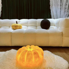 Yellow pumpkin-shaped portable table lamp with built-in battery on a rug in a modern living room