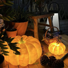 Yellow pumpkin-shaped portable table lamp with built-in battery on wooden table, surrounded by plants and pinecones, YH Lamps modern home lighting.