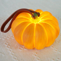 Yellow pumpkin-shaped USB portable table lamp with leather strap from YH Lamps on fabric.