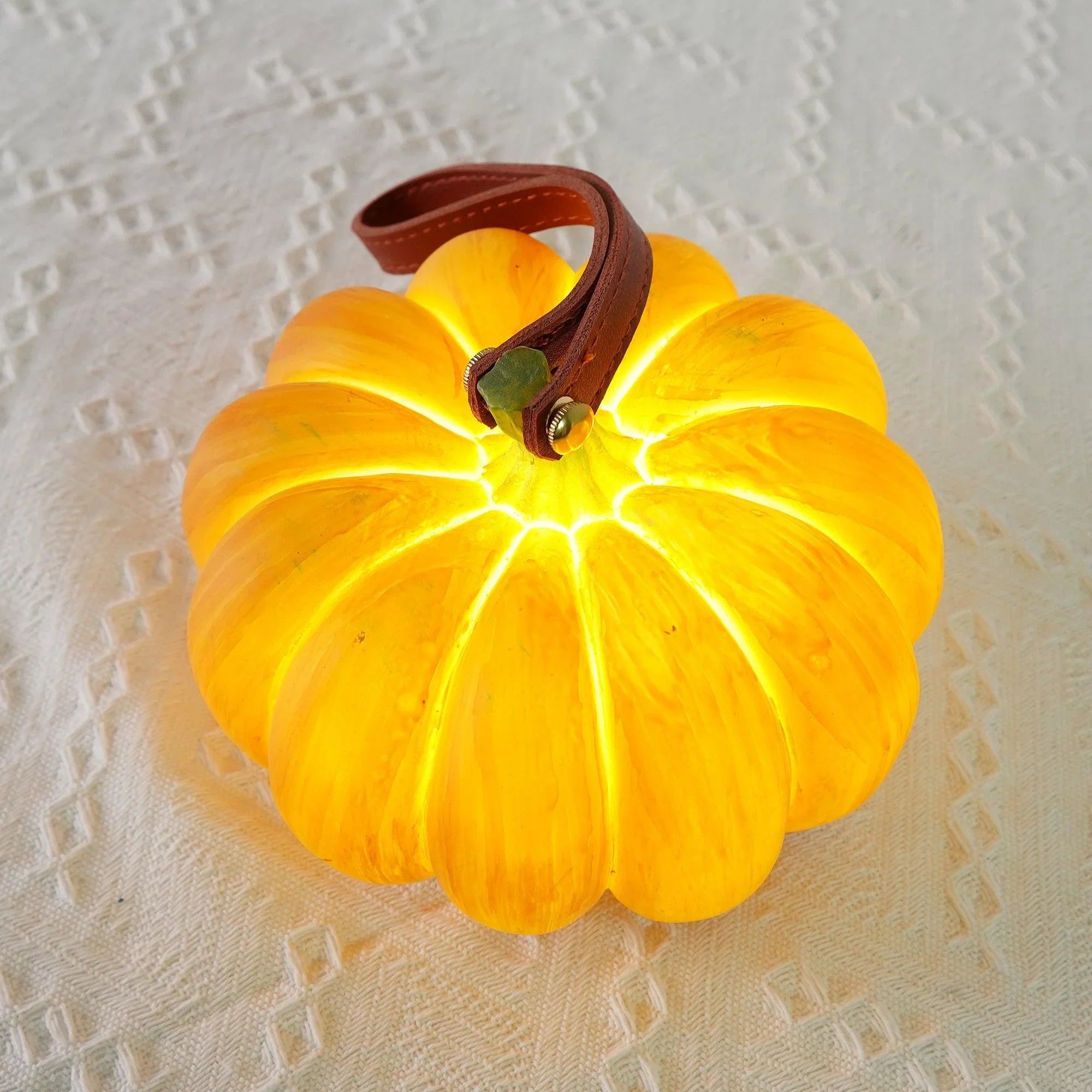 Yellow pumpkin-shaped portable table lamp with leather handle on textured white surface, YH Lamps