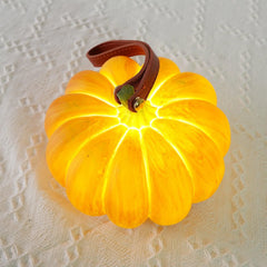 Yellow pumpkin-shaped portable table lamp with leather handle on textured white surface, YH Lamps