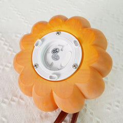 Yellow pumpkin-shaped portable table lamp with USB port and built-in battery on white fabric