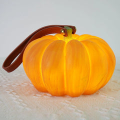 Yellow pumpkin-shaped portable table lamp with brown handle on a textured white surface