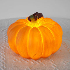 Yellow pumpkin-shaped portable table lamp with leather handle on textured white surface