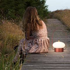 Modern dark red portable table lamp with soft glow on wooden path outdoors, YH Lamps