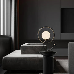 Modern double ring designer table lamp with glowing orb on black stand in contemporary living room