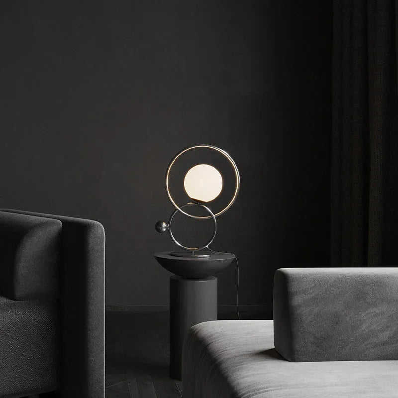 Modern double ring walnut table lamp with globe light on pedestal in dark living room