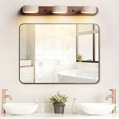 Modern bathroom with walnut color 3-light wall lamp above rectangular mirror, marble sinks, and copper faucets