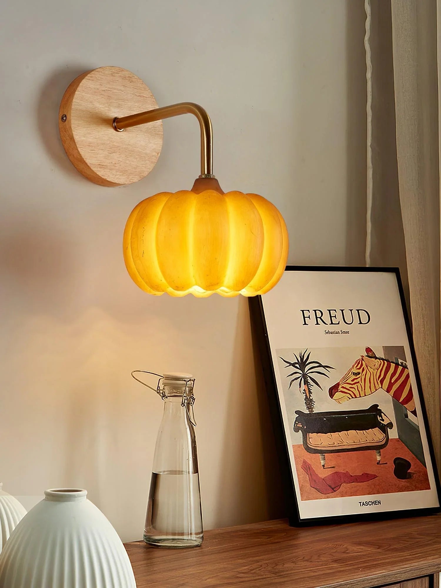 Modern yellow gold pumpkin-shaped wall lamp by YH Lamps, mounted above a wooden table.