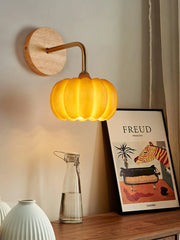 Modern yellow gold pumpkin-shaped wall lamp by YH Lamps, mounted above a wooden table.