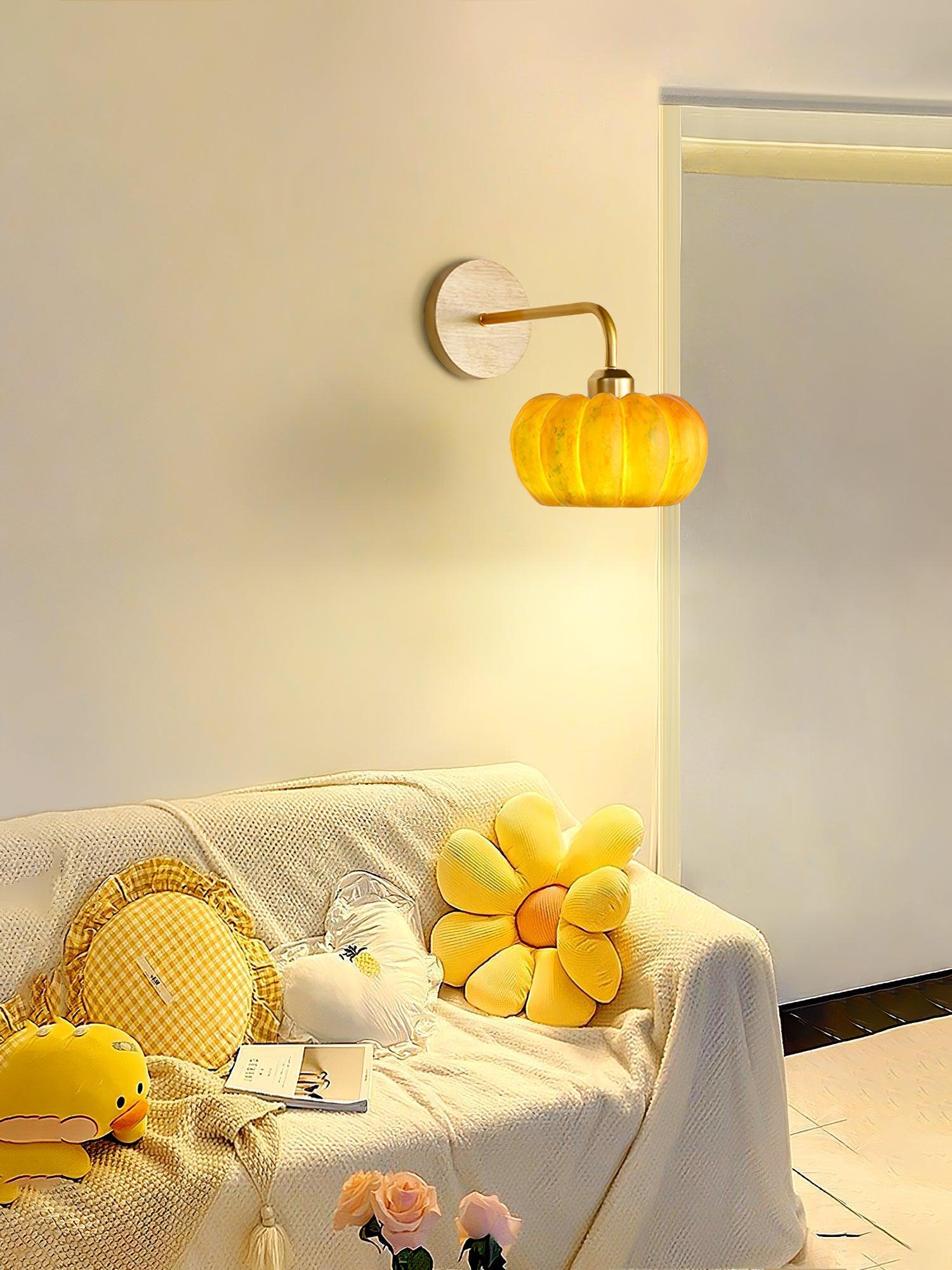 Yellow gold pumpkin wall lamp by YH Lamps above cozy sofa with plush pillows and flowers