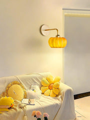 Yellow gold pumpkin wall lamp by YH Lamps above cozy sofa with plush pillows and flowers