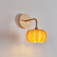Yellow gold pumpkin-shaped wall lamp with wood base from YH Lamps on a white wall.