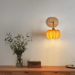 Yellow gold pumpkin wall lamp by YH Lamps, modern sconce on white wall above wood cabinet