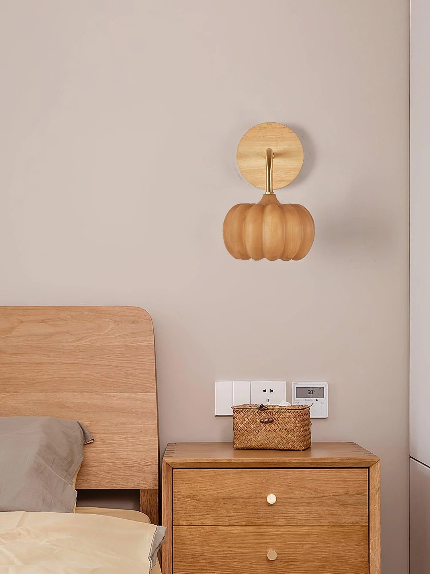 Modern yellow gold pumpkin wall lamp above wooden nightstand and bed in cozy bedroom