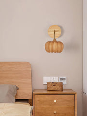 Modern yellow gold pumpkin wall lamp above wooden nightstand and bed in cozy bedroom