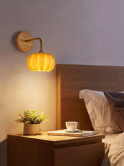 Yellow gold pumpkin wall lamp above modern wooden bedside table with plant and cup