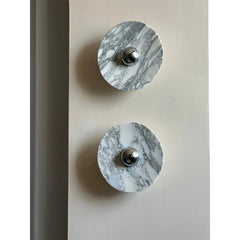 Modern chrome and marble wall lamps with round touch switches, mounted on a light wall