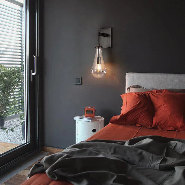 Modern raindrop glass wall sconce by YH Lamps in a stylish bedroom with dark walls and orange bedding
