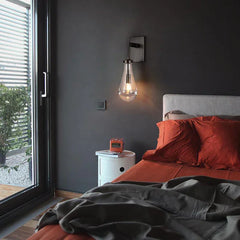 Modern raindrop glass wall sconce by YH Lamps in a stylish bedroom with dark walls and orange bedding