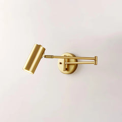 Gold swing arm wall sconce with cylindrical shade and warm light on white wall