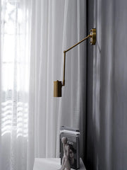 Modern brass swing arm wall lamp with wall switch illuminating gray wall near sheer white curtains and books on table